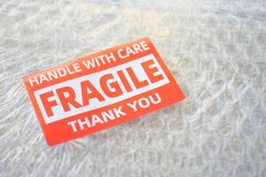A cardboard box marked with a caution label for fragile goods handling during shipping photo