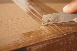 Carefully Opening a Package using a Utility Knife for Safe Unboxing and Extraction photo