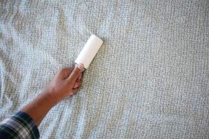 using an adhesive roller to remove lint and fluff from a bed . photo