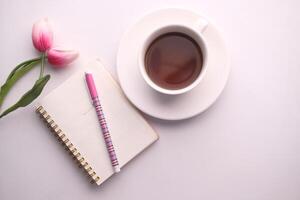 A Cozy Workspace Featuring Coffee, a Notepad, and Beautiful Tulips for Daily Inspiration photo