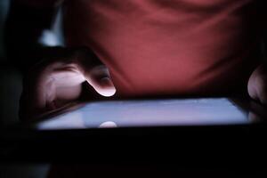 A closeup view of hands skillfully using a tablet device in a low light environment photo