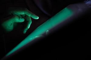 Close up of hacker hand stealing data from digital tablet photo