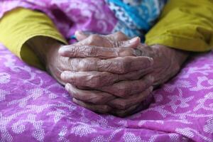 Elderly Hands Gently Resting on a Beautifully Colorful Piece of Fabric Displaying Patterns photo