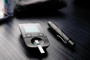 Here is a Diabetes Monitoring Device featuring a Test Strip and Pen placed on the Table photo