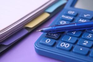 On the table, there is a calculator alongside a pen, notepad, and a variety of colorful paper photo
