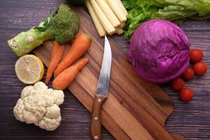 A selection of Fresh Vegetables, along with a Knife, placed thoughtfully on a Wooden Cutting Board photo
