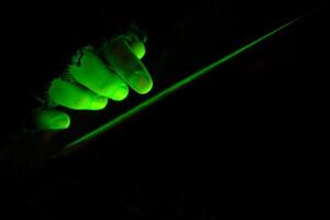 An Illuminated Green Hand Gripping a Blade in the Depths of Darkness Surrounding It photo
