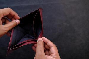 An empty wallet held in hands symbolizes the challenges and difficulties of financial struggles photo
