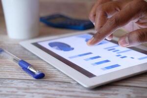Conducting a detailed analysis of data on a tablet device using various business charts and graphs photo
