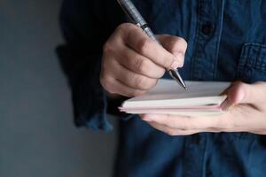 A person writes in a notebook with a pen in a casual setting that inspires creativity photo
