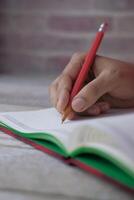 A Person Engaged in Writing in Their Notebook While Using a Red Pencil to Create Ideas photo