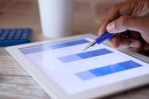 Analyzing data on a tablet with a stylus and calculator in a professional office setting photo