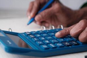 In the process of calculating finances using a blue calculator alongside a notepad for notes photo