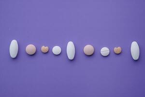 A Collection of Assorted Pills and Tablets Lying on a Deep Purple Background Surface photo
