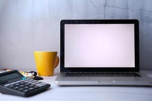 A sleek and minimalist workspace featuring a laptop, a coffee mug, and a calculator photo