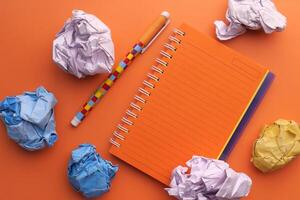 A Creative Workspace featuring a Notebook and Crumpled Papers all around it for inspiration photo