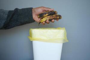 Properly Discarding Overripe Bananas into the Trash Bin to Maintain Cleanliness and Hygiene photo