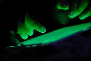 A closeup view of hands interacting with a glowing electronic device in the darkness of night photo