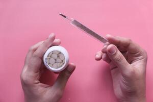 A person skillfully holds a pen while managing a container of various round objects photo