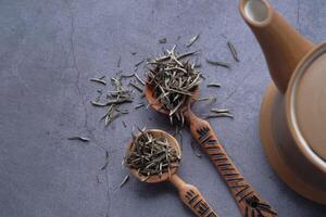A Beautiful Arrangement of Tea Leaves and a Teapot on a Gray Surface for Brewing photo