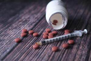Medical Supplies A combination of Pills and a Syringe arranged on a Wooden Background surface photo