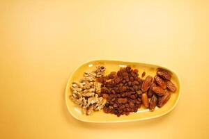 A vibrant assortment of assorted nuts and dried fruits beautifully displayed on a yellow background photo