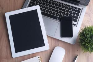 A modern workspace with a laptop, tablet, and smartphone on a sleek wooden desk photo