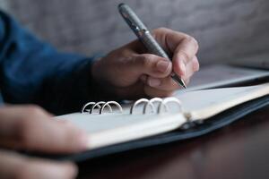 A CloseUp Image Showing Hands Actively Writing in a Notebook Using a Pen as a Tool photo