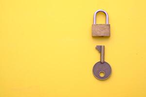 A Golden Padlock with a Key on a bright Yellow Background symbolizes security and protection photo
