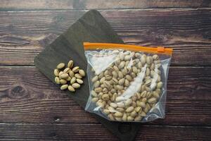 A variety of Assorted Nuts displayed in a Clear Bag resting on a Wooden Surface background photo
