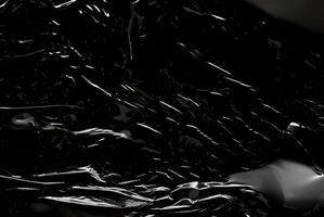 Dark abstract texture with glossy, reflective surfaces creating sharp highlights and flowing lines. photo