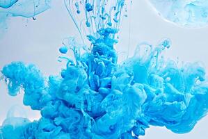 Abstract closeup of vibrant blue ink swirling and dispersing in water, creating cloud-like shapes in a fluid dynamic motion. photo