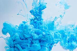 Abstract closeup of vibrant blue ink swirling and dispersing in water, creating cloud-like shapes in a fluid dynamic motion. photo