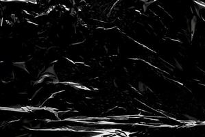 Dark abstract texture with glossy, reflective surfaces creating sharp highlights and flowing lines. photo