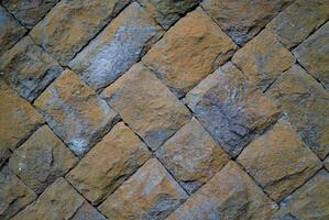 Close-up of a rustic stone wall with natural texture, ideal for backgrounds, architectural, or design elements. photo
