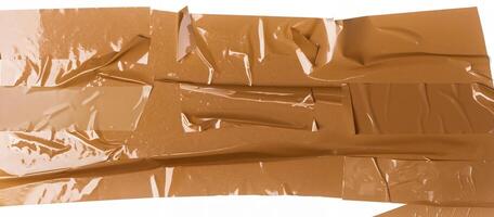 Close-up of a wrinkled brown adhesive tape strip with glossy surface on a plain white backdrop. photo