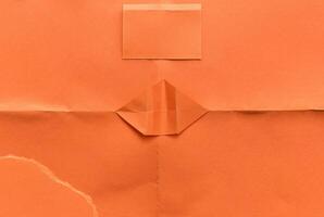 Minimal orange paper surface with visible folds and creases, ideal for backgrounds or design elements. photo
