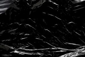 Dark abstract texture with glossy, reflective surfaces creating sharp highlights and flowing lines. photo
