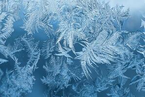 Detailed macro view of intricate frost patterns on a window surface during winter, forming natural ice crystals. photo
