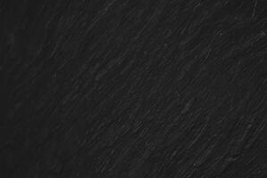 Dark textured slate surface, ideal for use as a background in design, with a subtle and natural stone texture. photo