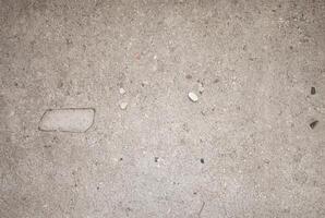 Close-up of plain concrete surface with small stones and rough texture, suitable for backgrounds and construction projects. photo
