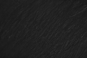 Dark textured slate surface, ideal for use as a background in design, with a subtle and natural stone texture. photo