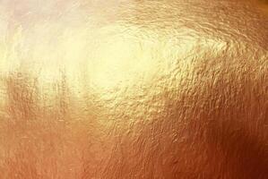Close-up of textured gold surface with a metallic shine, ideal for use in luxury backgrounds, design, and creative projects. photo