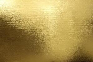 Shiny gold foil texture with a smooth, reflective surface ideal for backgrounds or luxurious designs. photo
