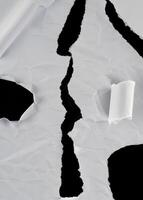 Close-up of torn white paper with a jagged tear down the center, revealing a black background. Suitable for abstract or background use. photo