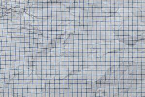 Close-up of crumpled white paper with a blue grid pattern, perfect for abstract backgrounds or textures. photo
