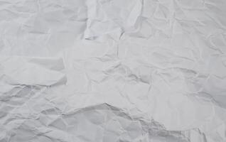 Crumpled white paper background with visible folds and creases, perfect for use in textures or design elements. photo