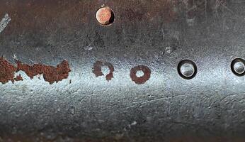 Close-up of a rough metallic surface featuring scratches, dents, and weathered texture, ideal for industrial backgrounds. photo