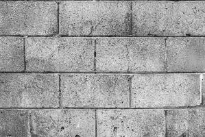 Black and white image of rough concrete block wall texture with visible wear and marks. photo