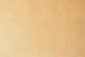 Beige textured wall surface close-up, ideal for use in backgrounds, interior design, and construction projects. photo
